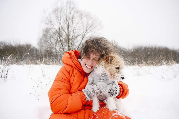 Happy woman embracing dog on snowfield