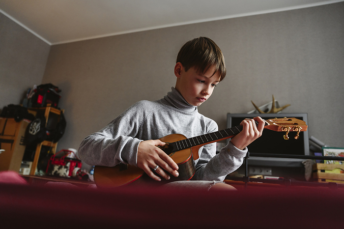 Boy playing ukulele at home