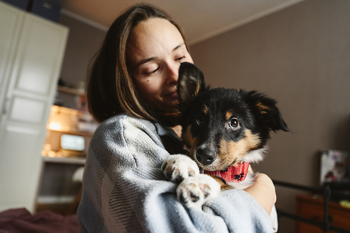 Woman holding dog in arms at home