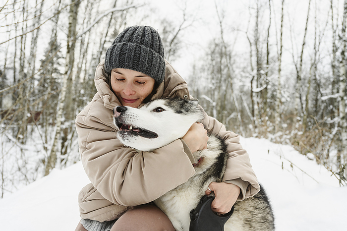 Woman embracing husky dog in winter