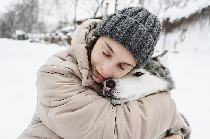 Woman embracing husky dog in winter