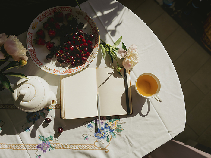 Diary near teapot and fruits on table at home