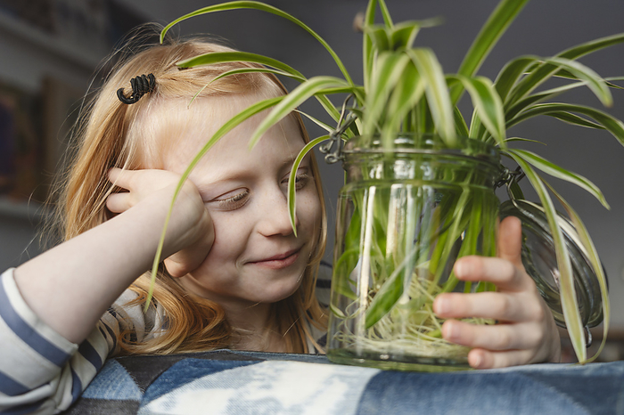 Smiling girl with spider plant at home