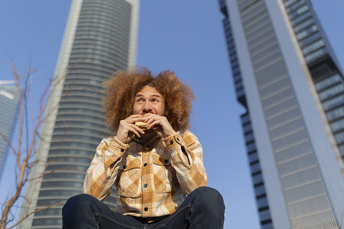 Man eating sandwich in front of buildings