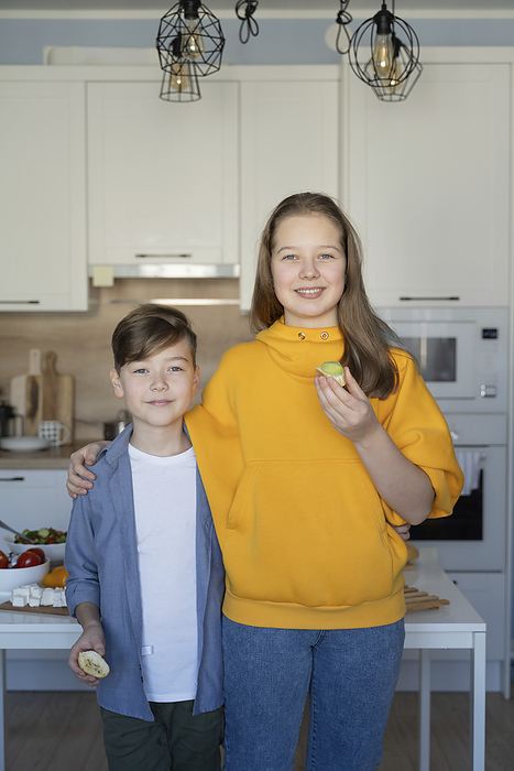 Smiling sibling standing in kitchen at home