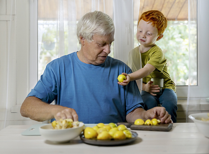 Boy passing fruit to grandfather at home