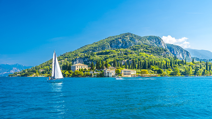 Italy Italy, Veneto, Punta San Vigilio, Lake Garda in summer with mountain and single sailboat in background