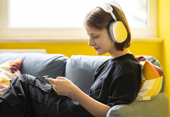 Girl listening to music through wireless headphones at home