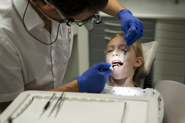 Dentist doing dental checkup of girl at medical clinic
