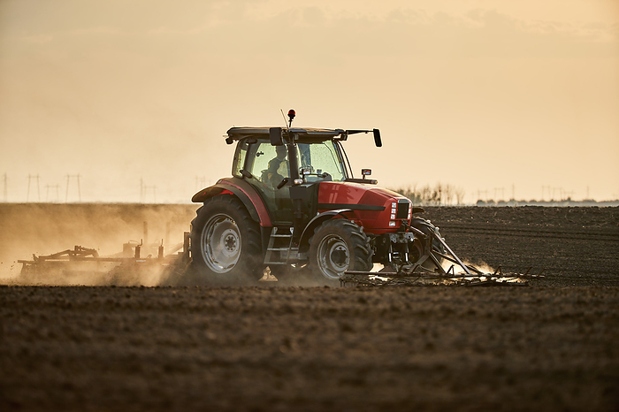 Farmer in tractor cultivating and plowing field