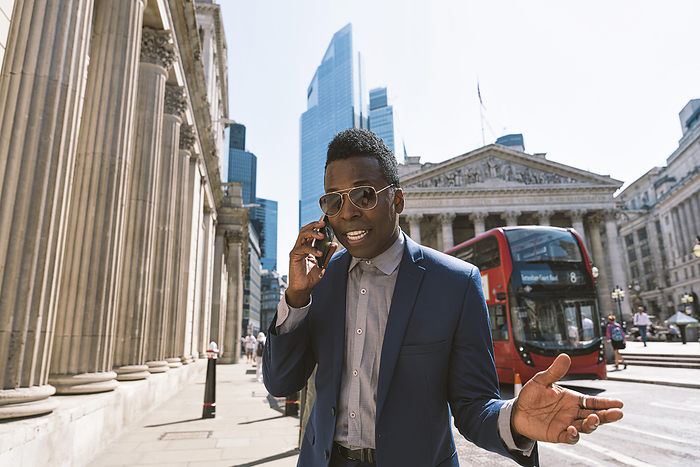 Mature businessman gesturing and talking on smart phone in London city
