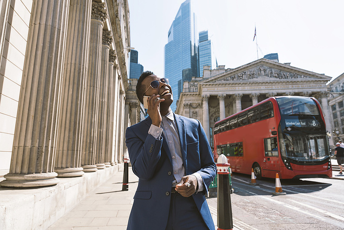 Happy businessman talking on mobile phone in London city