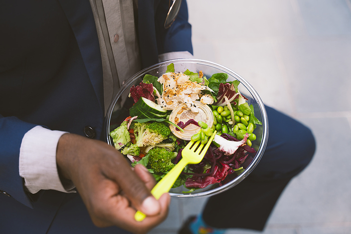 Businessman holding fork and having bowl of salad