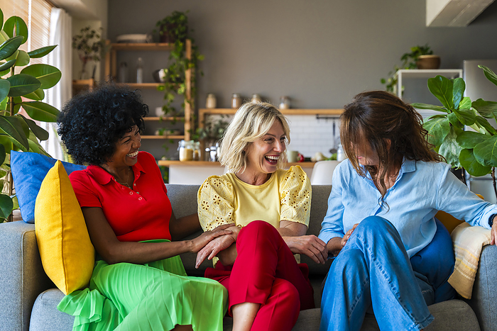 Cheerful senior woman having fun with friends sitting on sofa at home