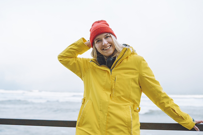 Happy young woman wearing winter jacket by sea