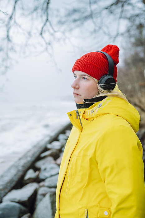 Thoughtful woman wearing wireless headphones at beach