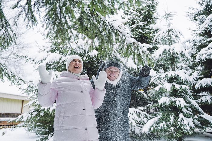 Carefree mature couple playing with snow in winter