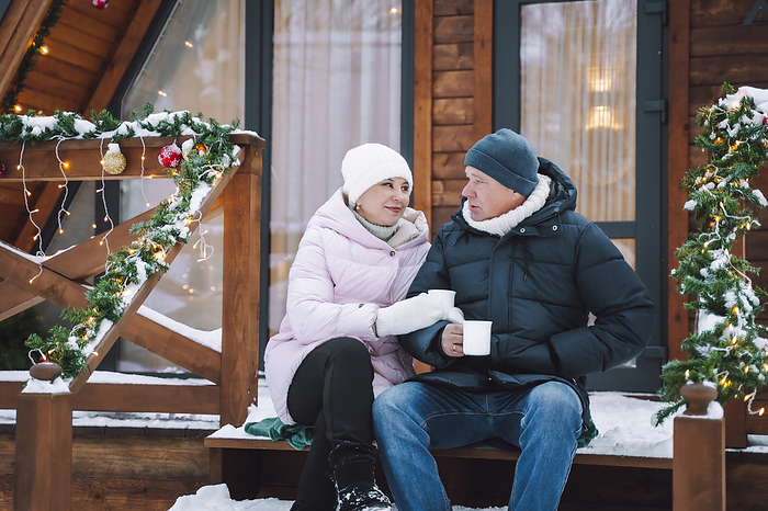 Mature couple having tea sitting on porch of log cabin