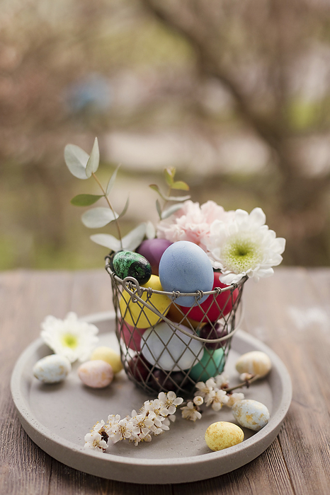 Colorful Easter eggs with flower decoration in basket on tray