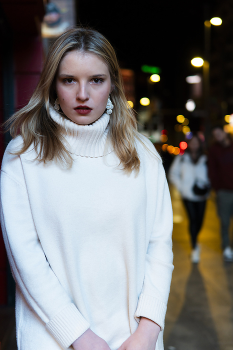 Confident woman wearing turtleneck and standing in city at night