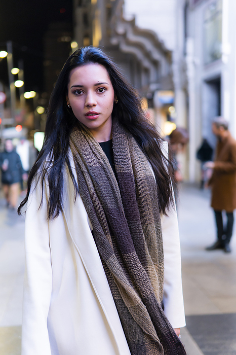 Young woman with long black hair standing at street in city