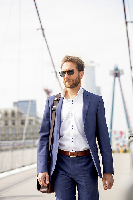 Businessman wearing sunglasses and standing on bridge