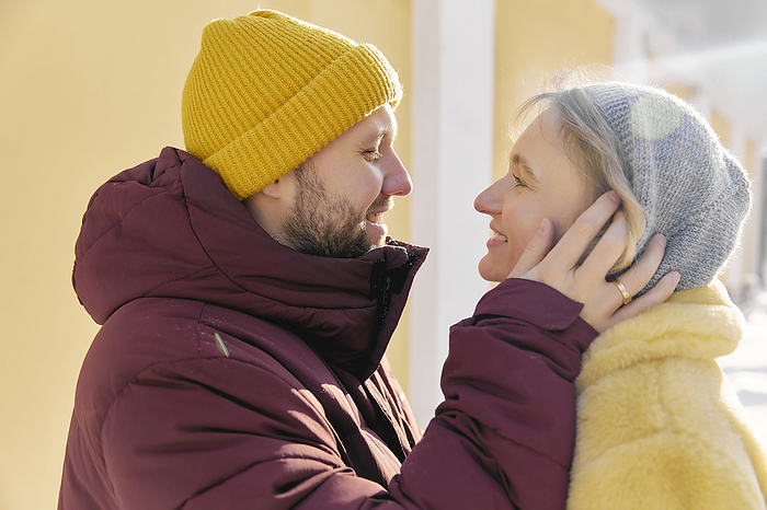 Happy man embracing woman in winter on sunny day