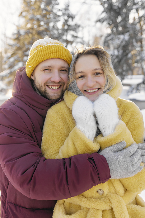 Smiling man hugging woman in winter forest