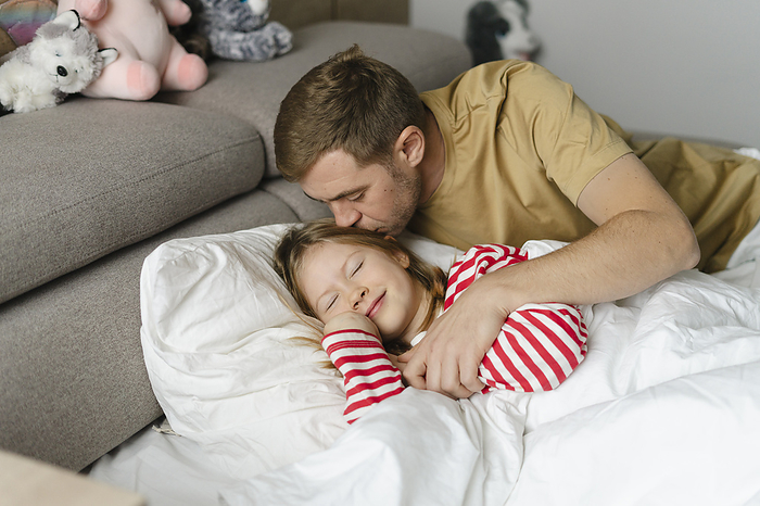 one day in a big family  morning and evening with dad getting ready for school, snack, dad resting, all together, children s energy and parents  patience Father kissing daughter sleeping on bed at home