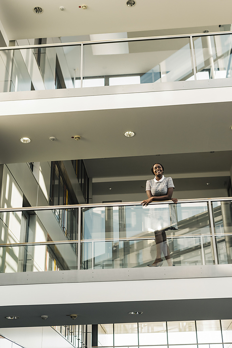 Businesswoman leaning on glass railing in office