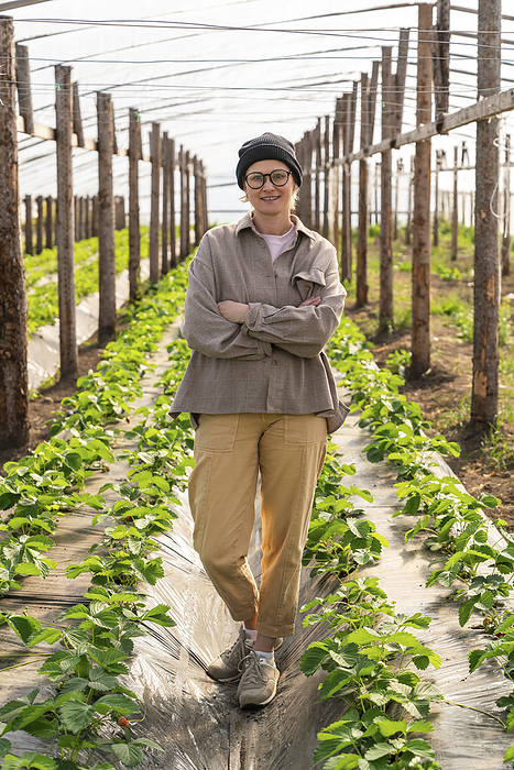 Confident farmer standing with arms crossed in greenhouse