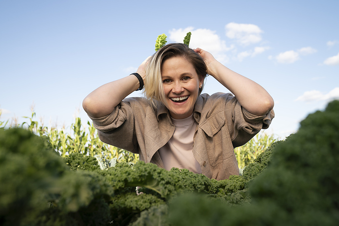 Happy farmer playing with kale leaves in farm