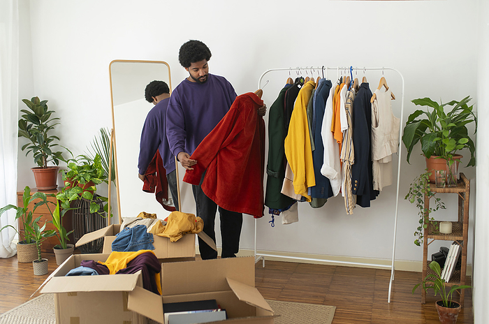 Young man decluttering clothes at home