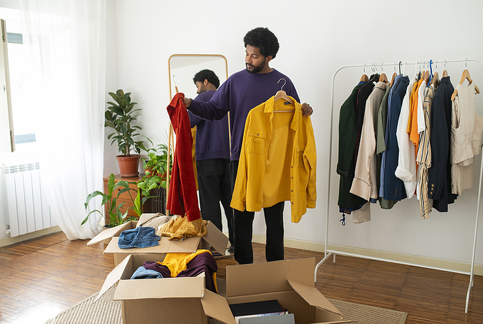 Young man organizing and decluttering clothes at home