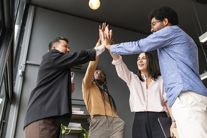 Happy colleagues giving high-five to each other in office