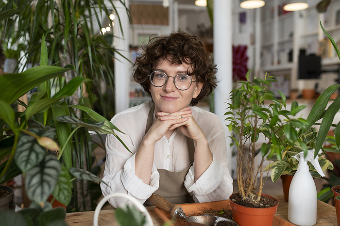 Smiling botanist leaning on elbows at plant shop