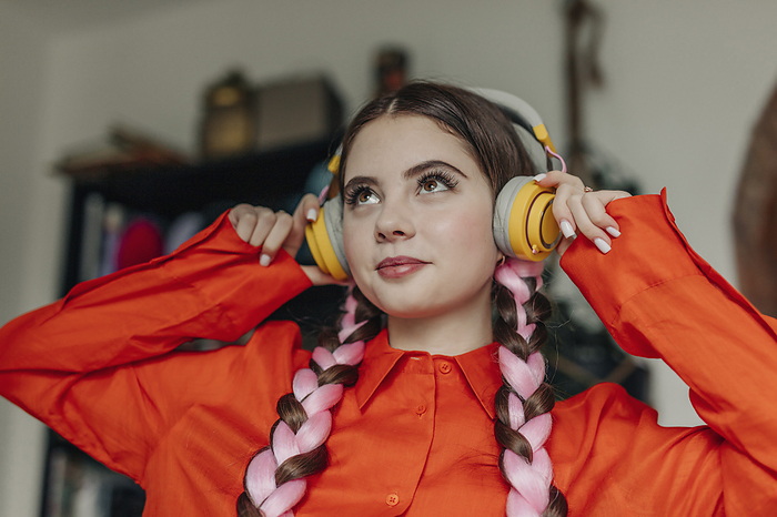 Smiling woman wearing wireless headphones listening to music at home