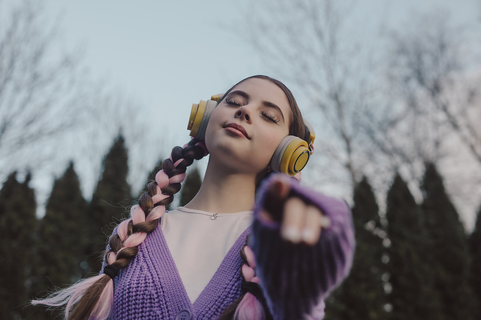 Smiling young woman with eyes closed listening to music at sunset