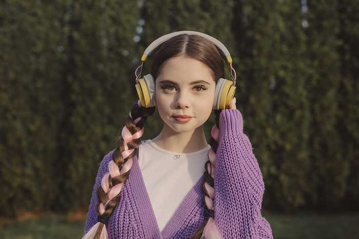 Young woman wearing wireless headphones and listening to music