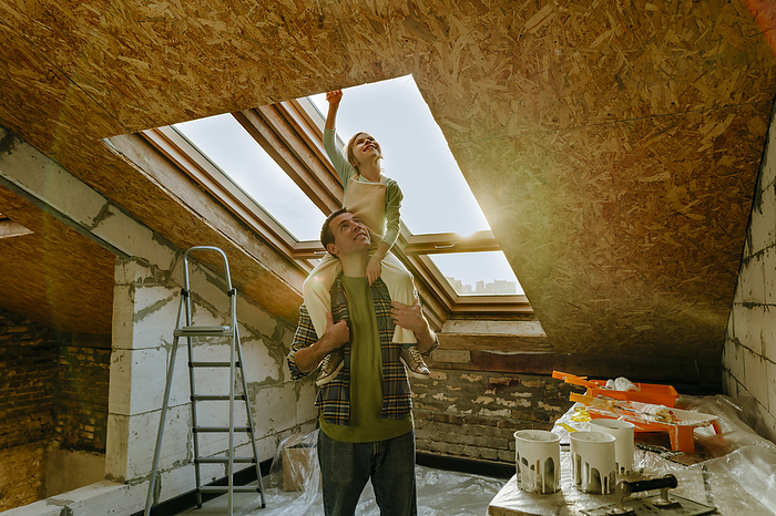 Father carrying daughter on shoulders in room under renovation