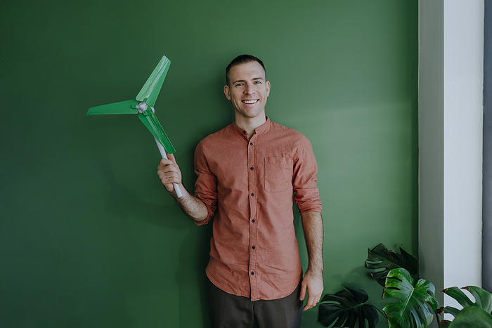 Freelancer standing with wind turbine model in front of green wall