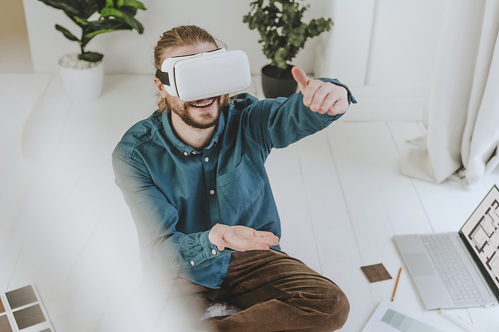 Smiling interior designer wearing VR glasses and gesturing at office