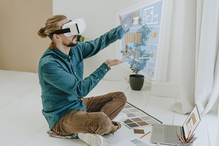Interior designer preparing project through VR glasses sitting on floor at office