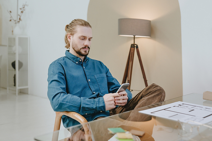Interior designer using smart phone sitting on chair at office