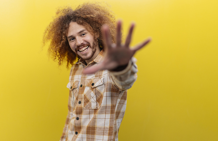 Man showing stop gesture in front of yellow wall