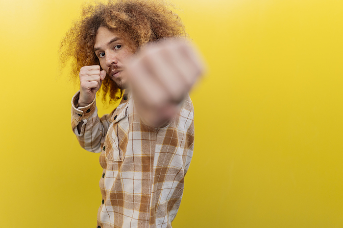Man punching in front of yellow wall