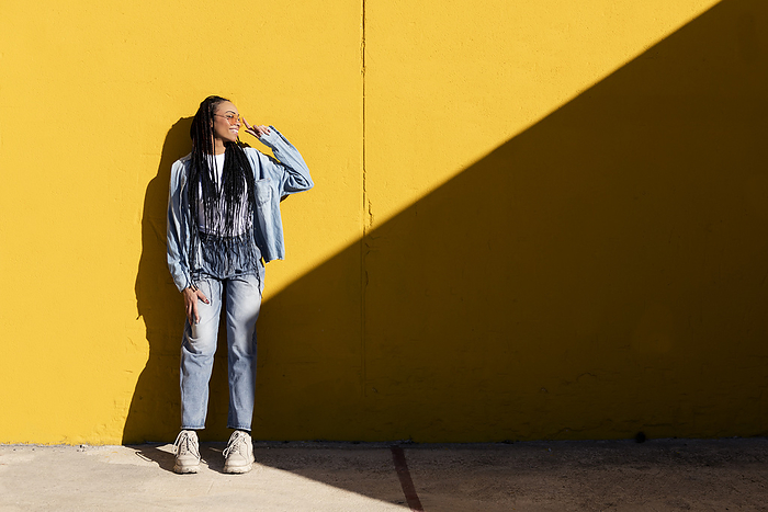 Smiling woman leaning on yellow wall