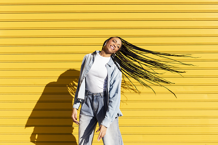 Young woman tossing hair in front of corrugated shutter