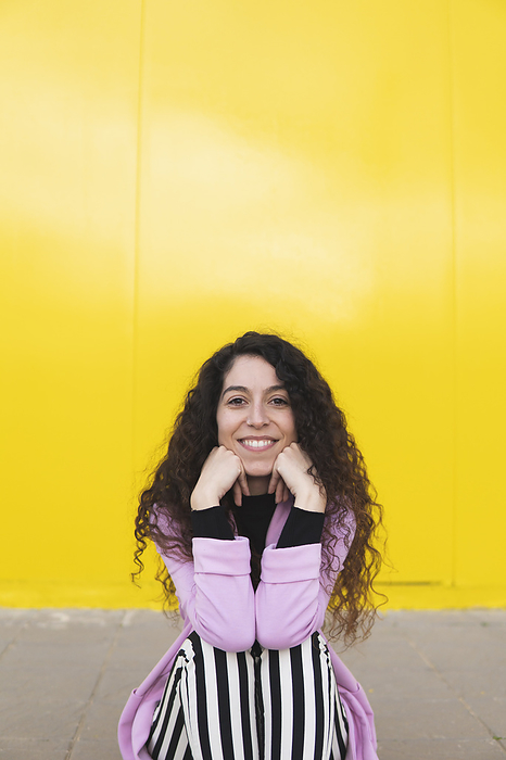 Woman leaning on elbows and sitting in front of yellow wall