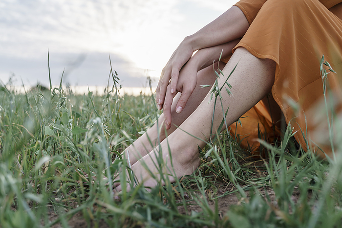 Woman with bare feet sitting in corn field